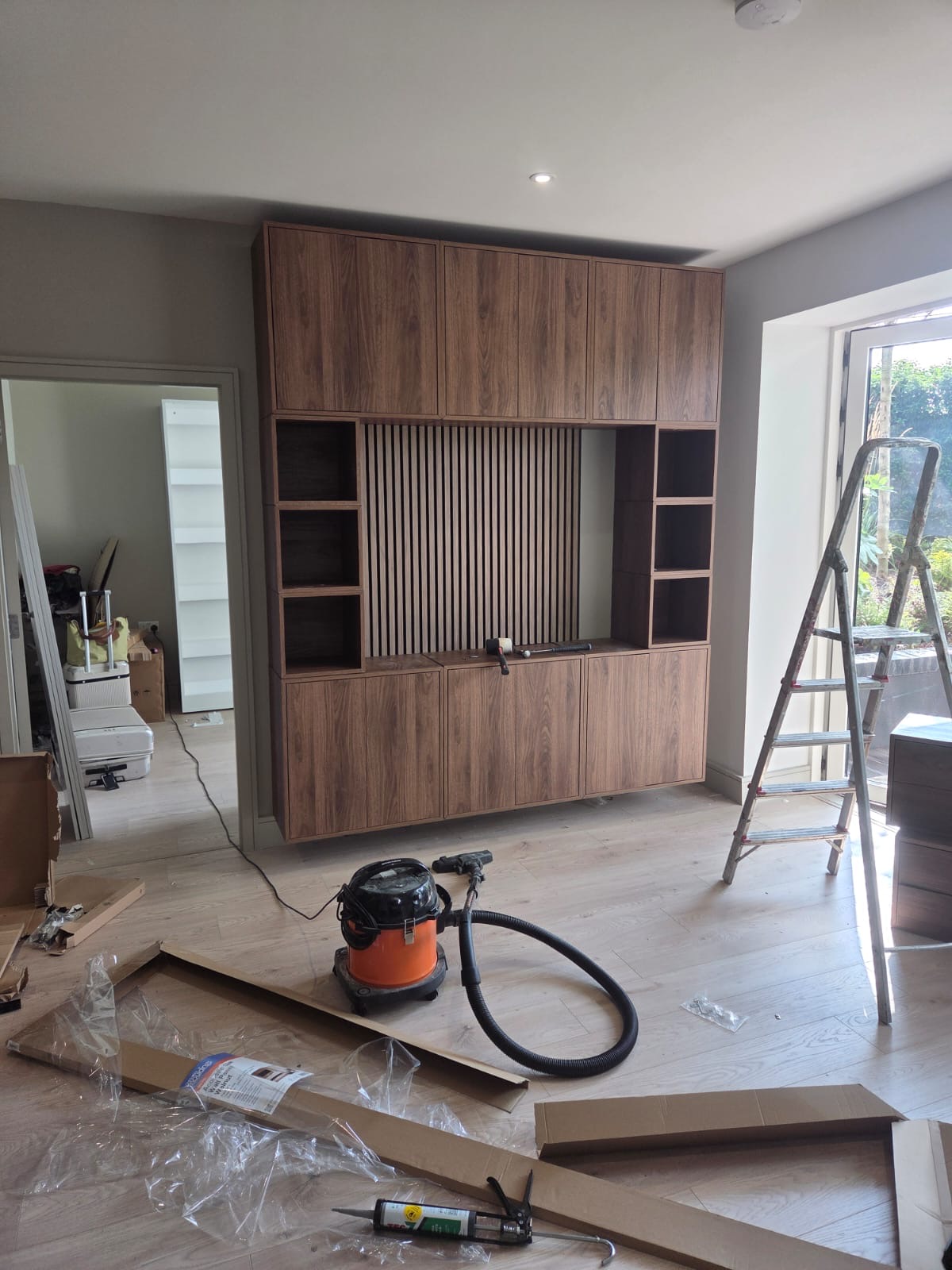 Walnut media wall unit with slat panelling and cabinet storage assembled and wall mounted in Dublin living room