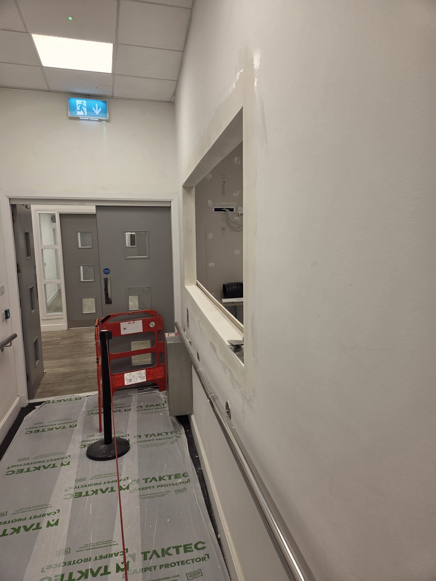 Freshly plastered corridor walls in Dublin office renovation with carpet protection