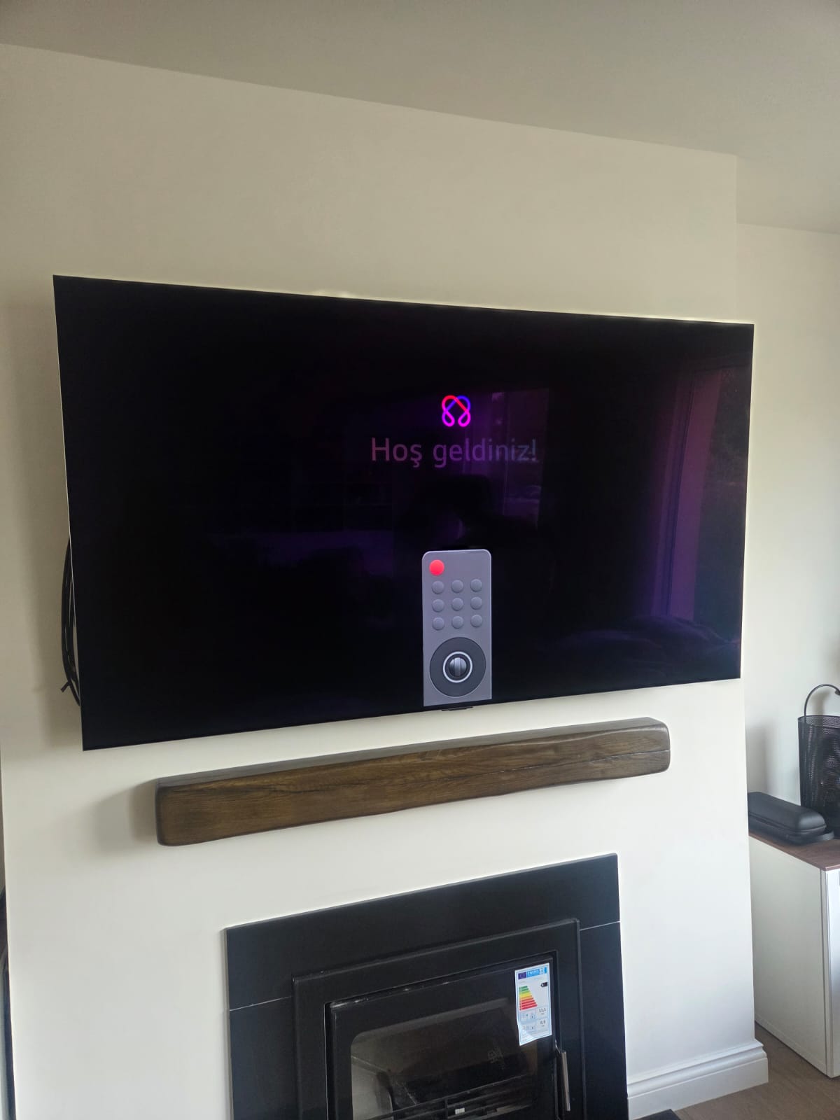 Large flat screen TV wall mounted above a fireplace with a solid timber mantel beam below