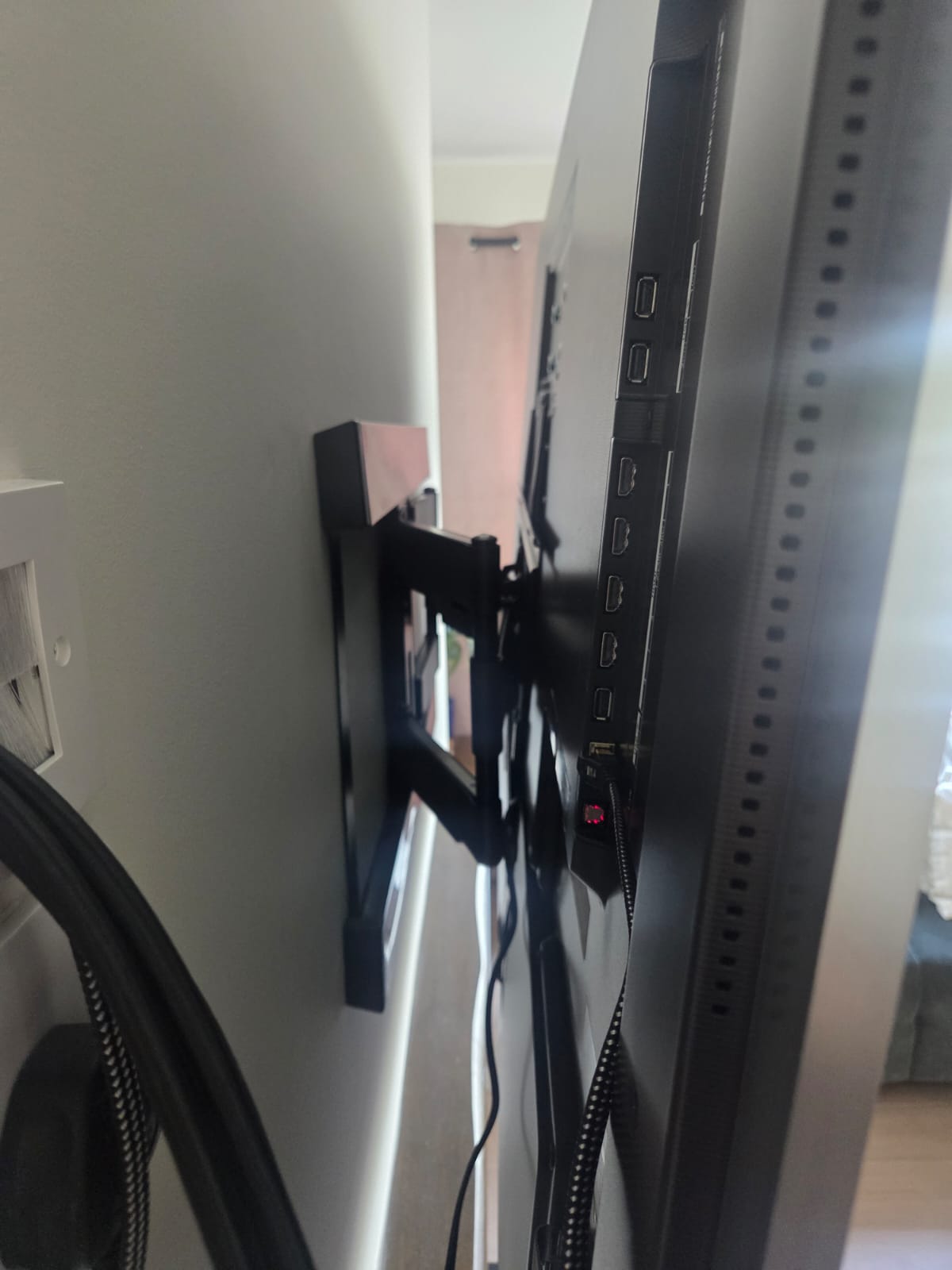 Full motion TV bracket extended from the wall with cables routed down the back of the screen